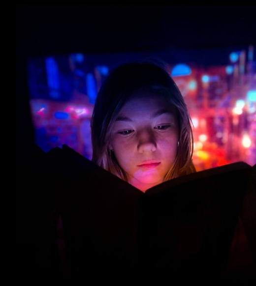 Person reading a book illuminated by colorful light